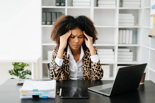 Stock image African Woman who is tired and overthinking from working with tablet and laptop at modern office