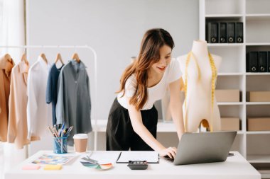 Genç Asyalı terzi kadın elbise atölyesinde çalışıyor. Kadın 