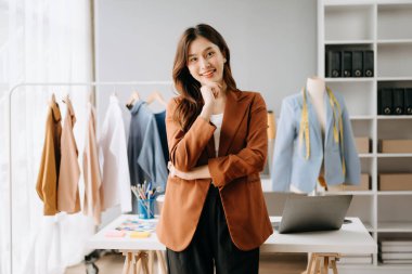 Asyalı moda kadın tasarımcısı kendi atölyesinde duruyor.