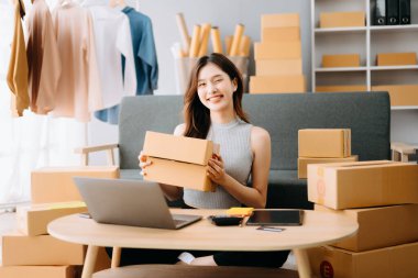 Başlangıçta küçük işletme KOBİ 'si, akıllı telefon veya tablet kullanan girişimci sahibi Asyalı kadın paket ürün kutusu hazırlamak için çevrimiçi alışveriş siparişini alır ve kontrol eder.
