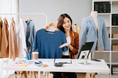 Asyalı kadın dijital tablette video görüşmesi sırasında kıyafetleri tanıtıp satıyor