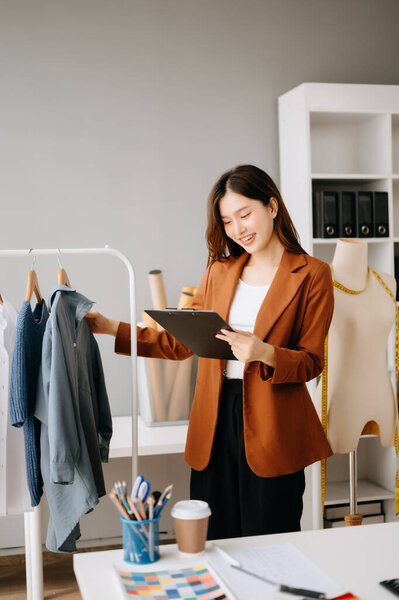 Азиатский модельер женщина проверяет одежду и держит папку