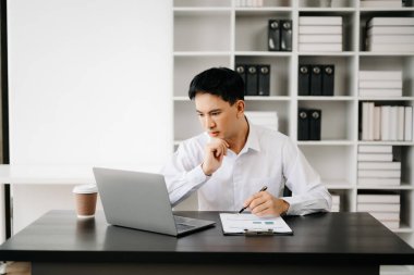 Genç Asyalı işadamı modern ofiste belgelerle çalışıyor. Vergi, rapor, muhasebe, istatistik ve analitik araştırma kavramı