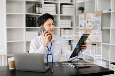 İş adamı sanal diyagram çizelgesi çizerek görevleri güncelliyor. Modern ofiste dizüstü bilgisayarla çalışan genç bir Asyalı.