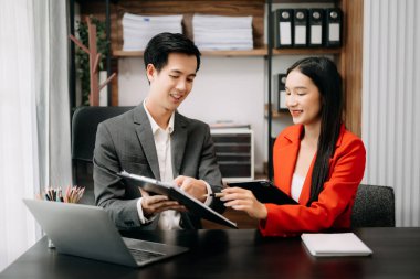 Asyalı iş arkadaşları dizüstü bilgisayar ve tablet kullanıyorlar. Takım çalışması, finansal pazarlama ekibi, modern ofis odasında otururken.