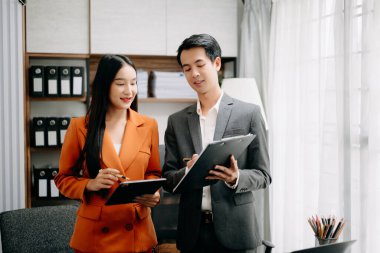 İki Asyalı işadamı, modern ofisteki tablet bilgisayar ile yatırım projesinin çalışma ve planlama stratejisini tartıştı.