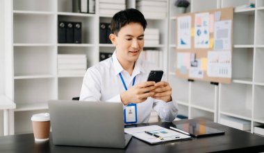 Genç Asyalı işadamı modern ofiste belgelerle çalışıyor. Vergi, rapor, muhasebe, istatistik ve analitik araştırma kavramı