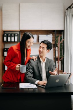 Asyalı iş arkadaşları dizüstü bilgisayar ve tablet kullanıyorlar. Takım çalışması, finansal pazarlama ekibi, modern ofis odasında otururken.