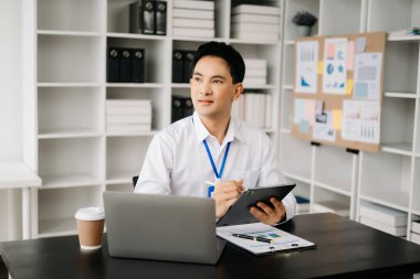 Genç Asyalı işadamı modern ofiste belgelerle çalışıyor. Vergi, rapor, muhasebe, istatistik ve analitik araştırma kavramı