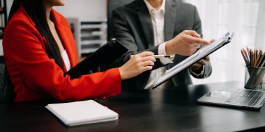 Akıllı telefon ve hesap makinesi olan ofis masasındaki iş belgeleri dijital tablet ve sosyal ağ diyagramı olan grafik işleri ve büroda çalışan verileri tartışan iki iş arkadaşı