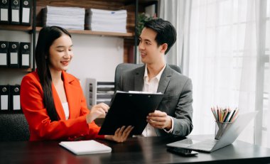 Asyalı iş arkadaşları dizüstü bilgisayar kullanıyor. Takım çalışması, finansal pazarlama ekibi, modern ofis odasında otururken.