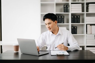 Genç Asyalı işadamı modern ofiste belgelerle çalışıyor. Vergi, rapor, muhasebe, istatistik ve analitik araştırma kavramı