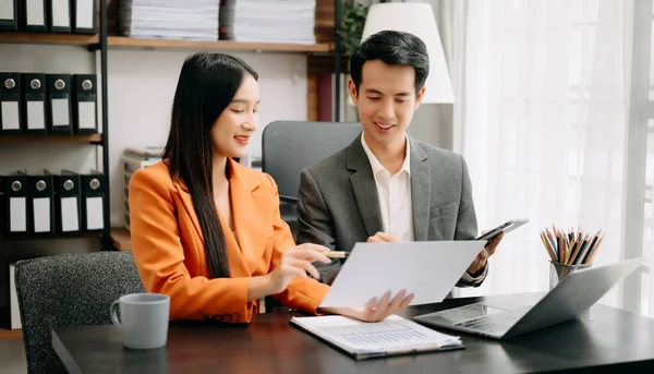 stock image Two Asian businesspeople discuss investment project working and planning strategy with tablet pc and  laptop computer in modern office.