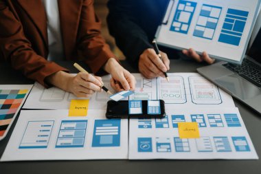  UX geliştiricisi ve ui tasarımcısı modern ofiste müşteri özeti ve renk kodu ile mobil uygulama arayüzü kablo tasarımı hakkında beyin fırtınası yapıyorlar