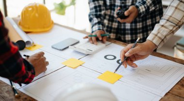 Engineer desk with object paper and tablet with blurry engineer teamwork hardworking to consults about their building project. in office