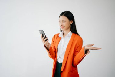 Beyaz arka planda, mutlu hisseden ve akıllı telefon tutan genç Asyalı kadının portre fotoğrafı reklam veya ürün için kullanılabilir, sunum konsepti