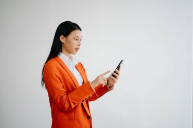 Beyaz arka planda, mutlu hisseden ve akıllı telefon tutan genç Asyalı kadının portre fotoğrafı reklam veya ürün için kullanılabilir, sunum konsepti