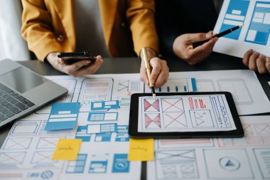 UI müteahhitlerinin projelerini dizüstü bilgisayar, akıllı telefon ve dijital tablet ile beyin fırtınası yaparken görüntülerini kapatın. Yaratıcı dijital geliştirme ajansı. Sanal simgeyle