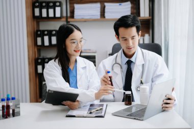 Tıp teknolojisi ekip toplantısı konsepti. Asyalı Doktor El, tıbbi endüstride akıllı telefon, modern dijital tablet ve grafik tableti arayüzü olan dizüstü bilgisayarla çalışıyor.
