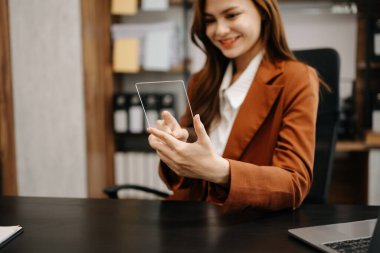 İş kadını ön tablette oturuyor, bilgisayarında finansal grafikler ve istatistikler var.