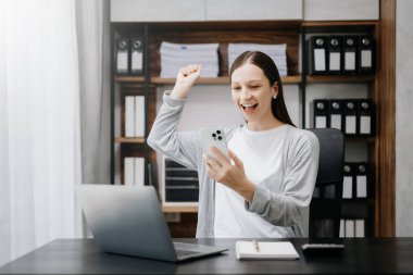 Kafkasyalı iş kadını cep telefonu kullanırken elleriyle mutluluğunu ifade ediyor. 