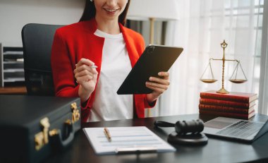 Adalet ve hukuk kavramı. Bir mahkeme salonunda kadın yargıç tokmak, akıllı telefon, dizüstü bilgisayar ve dijital tablet bilgisayarla çalışıyor. 