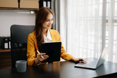 Kendine güvenen iş uzmanı çekici gülümseyen Asyalı kadın yaratıcı ofiste dijital tablet tutuyor..