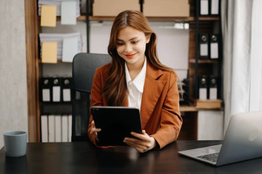 Kendine güvenen iş uzmanı çekici gülümseyen Asyalı kadın yaratıcı ofiste dijital tablet tutuyor..