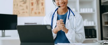 Çekici kadın doktor konuşuyor ve hastaya tıbbi tedaviyi ofisteki bir bilgisayarla anlatıyor.