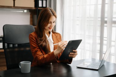 Kendine güvenen iş uzmanı çekici gülümseyen Asyalı kadın yaratıcı ofiste dijital tablet tutuyor..