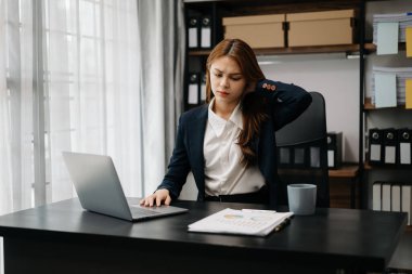 Ofis masasında uzun bir gün geçirdikten sonra boynu ağrıyan Asyalı genç işkadını ofis çalışanı. ofis sendromu kavramı