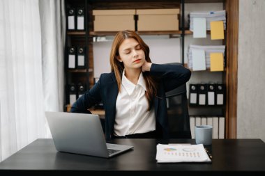 Ofis masasında uzun bir gün geçirdikten sonra boynu ağrıyan Asyalı genç işkadını ofis çalışanı. ofis sendromu kavramı