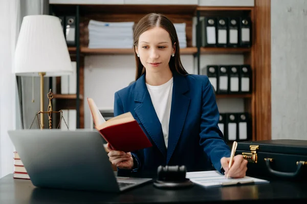 stock image Beautiful Caucasian Woman reading justice book and making notes with pen with working in office at table with laptop 