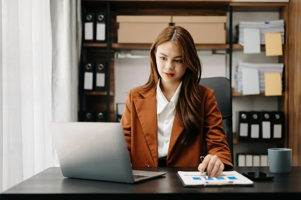 Confident business expert attractive smiling young Asian woman holding digital tablet  on desk in creative office.