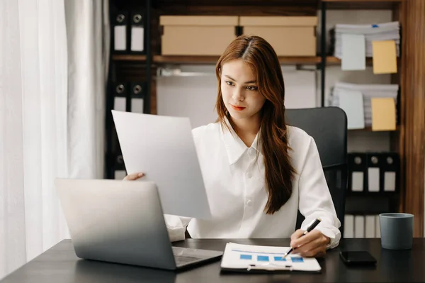 Confident business expert attractive smiling young Asian woman holding digital tablet  on desk in creative office.