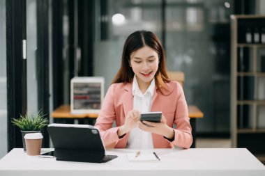 Ofiste tablet bilgisayar ve cep telefonu kullanarak finansal verileri analiz eden başarılı Asyalı iş kadını. Vergi, muhasebe, istatistik ve analitik araştırma kavramı