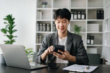 Genç Asyalı işadamı modern ofiste çalışan raporları analiz ediyor