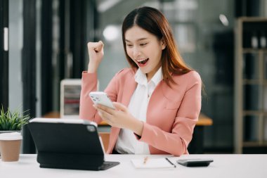 Ofiste tablet bilgisayar ve cep telefonu kullanarak finansal verileri analiz eden başarılı Asyalı iş kadını. Vergi, muhasebe, istatistik ve analitik araştırma kavramı