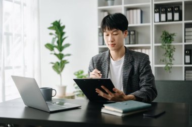 Genç Asyalı işadamı modern ofiste çalışan raporları analiz ediyor