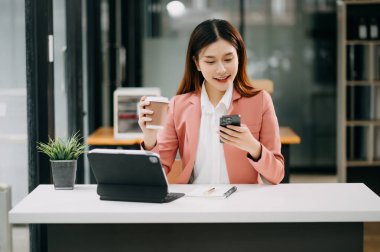 Ofiste tablet bilgisayar ve cep telefonu kullanarak finansal verileri analiz eden başarılı Asyalı iş kadını. Vergi, muhasebe, istatistik ve analitik araştırma kavramı