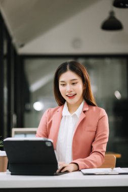 Ofiste tablet bilgisayar ve cep telefonu kullanarak finansal verileri analiz eden başarılı Asyalı iş kadını. Vergi, muhasebe, istatistik ve analitik araştırma kavramı