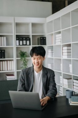 Genç işadamı ofiste dizüstü bilgisayarla çalışıyor.