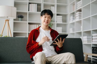 Genç ve çekici Asyalı adam evden çalışıyor.