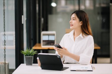 Ofiste tablet bilgisayar ve cep telefonu kullanarak finansal verileri analiz eden başarılı Asyalı iş kadını. Vergi, muhasebe, istatistik ve analitik araştırma kavramı