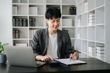 Genç Asyalı işadamı modern ofiste çalışan raporları analiz ediyor