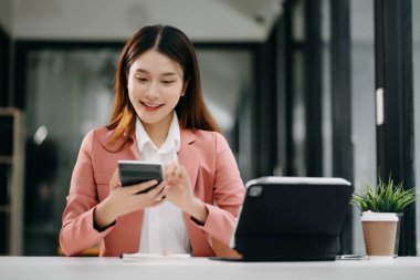 Ofiste tablet bilgisayar ve cep telefonu kullanarak finansal verileri analiz eden başarılı Asyalı iş kadını. Vergi, muhasebe, istatistik ve analitik araştırma kavramı