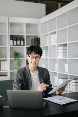 Bilgisayarla çalışan genç işadamı modern ofiste pazar araştırması yapıyor.