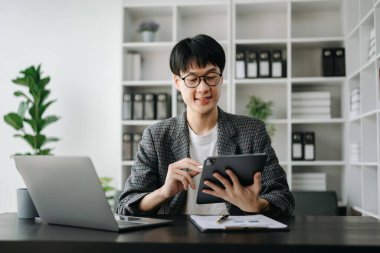 Bilgisayarla çalışan genç işadamı modern ofiste pazar araştırması yapıyor.