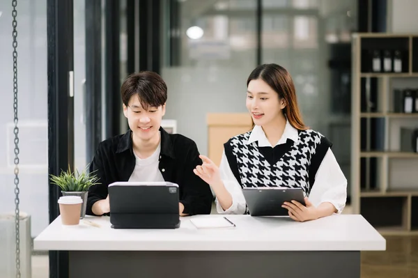 Asian businessman with female colleague using tablet in modern office room. Teamwork, financial marketing team