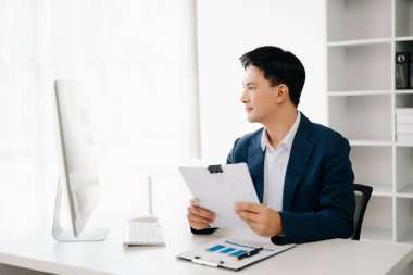 Genç Asyalı işadamı modern ofiste belgelerle çalışıyor. Vergi, rapor, muhasebe, istatistik ve analitik araştırma kavramı